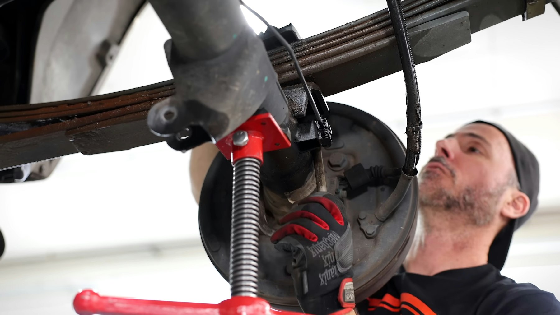 Mechanic working on a truck axle with the wheel and brake drum removed